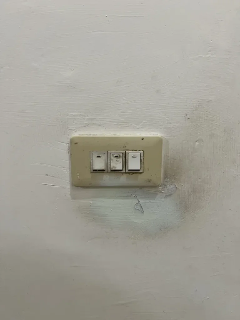 改造前的舊電燈開關，周圍牆面有污痕