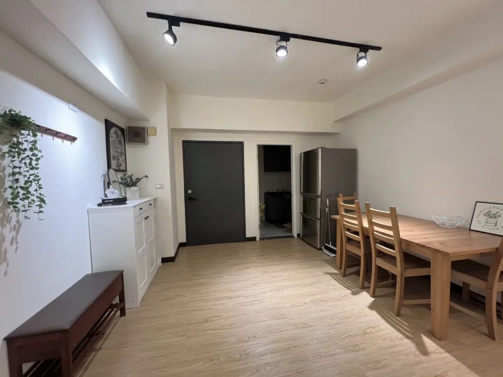 玄關與餐廳完成後的長軸視角，木紋地板、軌道燈、鞋櫃與餐桌